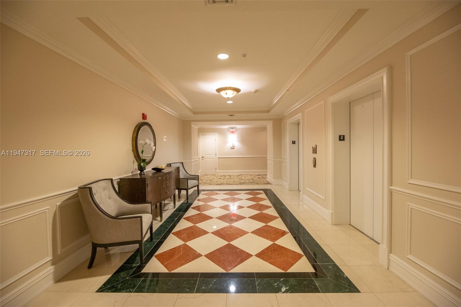 A hallway features a checkered floor, two armchairs, a console table, and an elevator — 16101 Emerald Estates Dr # 250, Weston FL 33331, WESTON, FL