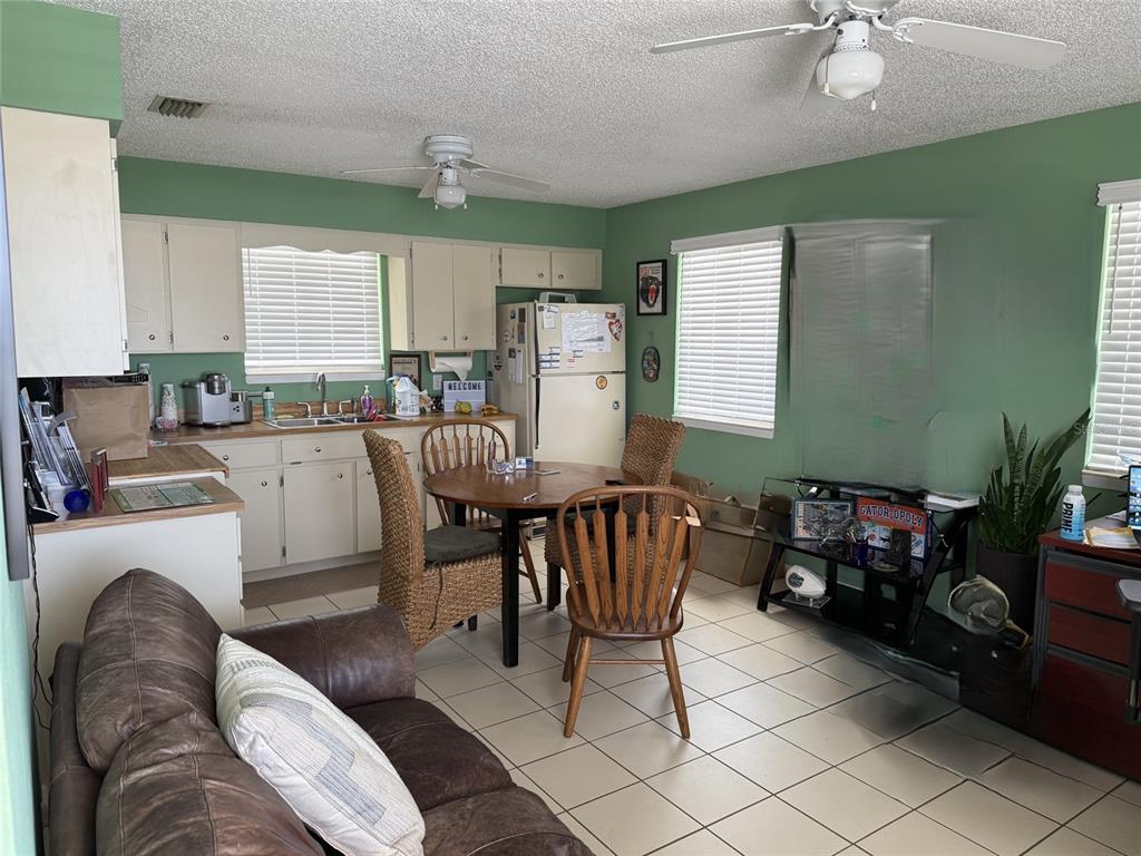 A kitchen and dining area with green walls, white cabinets, and tile flooring — 104 S 4TH STREET UNIT 104, FLAGLER BEACH, FL