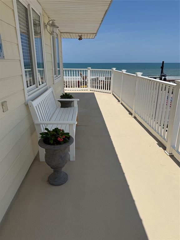 A white bench and a potted plant sit on a balcony overlooking the ocean — 104 S 4TH STREET UNIT 104, FLAGLER BEACH, FL