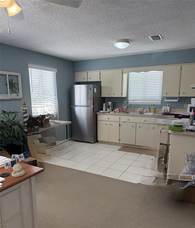 A kitchen with light-colored cabinets, stainless steel appliances, and a tiled floor — 104 S 4TH STREET UNIT 104, FLAGLER BEACH, FL