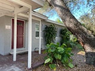 A red front door is visible on the exterior of a gray house with landscaping — 4390 68TH STREET N, ST PETERSBURG, FL