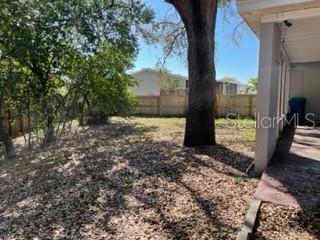 A backyard area with a large tree, a wooden fence, and a covered patio — 4390 68TH STREET N, ST PETERSBURG, FL