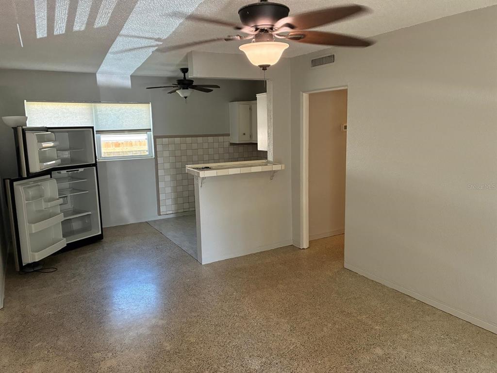 A kitchen with a breakfast bar and a refrigerator sits adjacent to a living area — 4390 68TH STREET N, ST PETERSBURG, FL