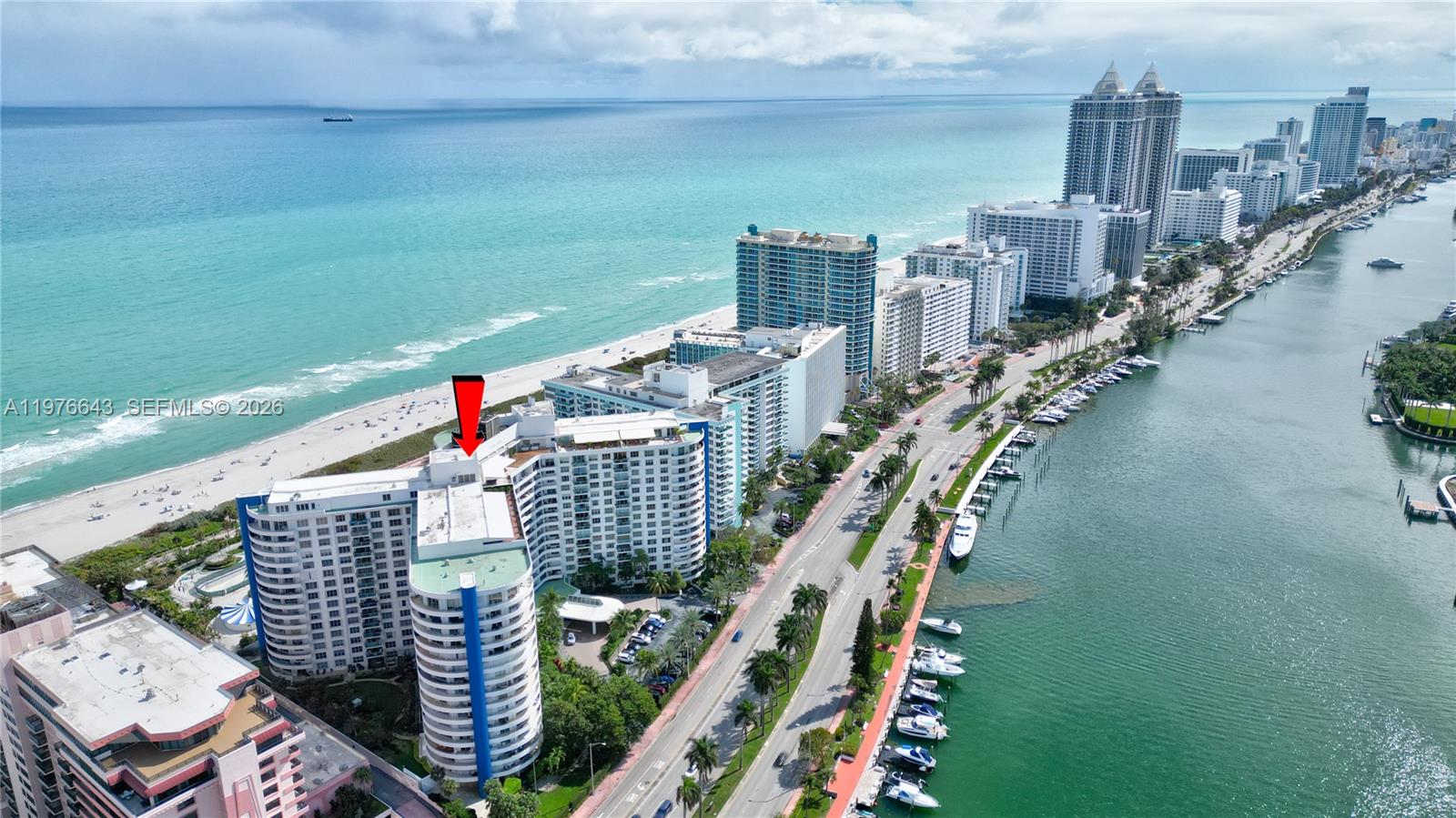 An aerial view shows a high-rise residential building situated between the ocean and a waterway — 5161 Collins Ave # 516, Miami Beach FL 33140, MIAMI BEACH, FL