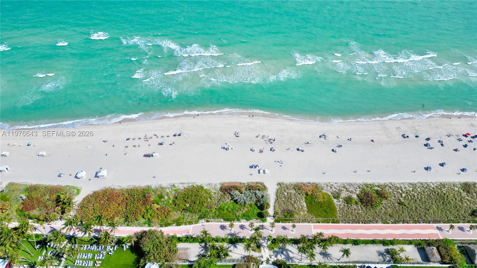 An aerial view shows a sandy beach with people, turquoise ocean water, and a walkway — 5161 Collins Ave # 516, Miami Beach FL 33140, MIAMI BEACH, FL