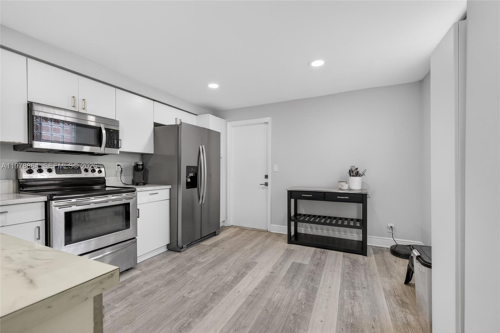 A kitchen features white cabinets, stainless steel appliances, and wood-look flooring — 1594 Barcelona Way # 18, Weston FL 33327, WESTON, FL