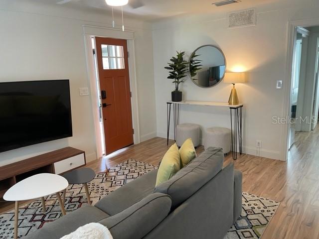 A living room features a gray sofa, a television, a console table, and a front door — 3646 6TH AVENUE N, ST PETERSBURG, FL