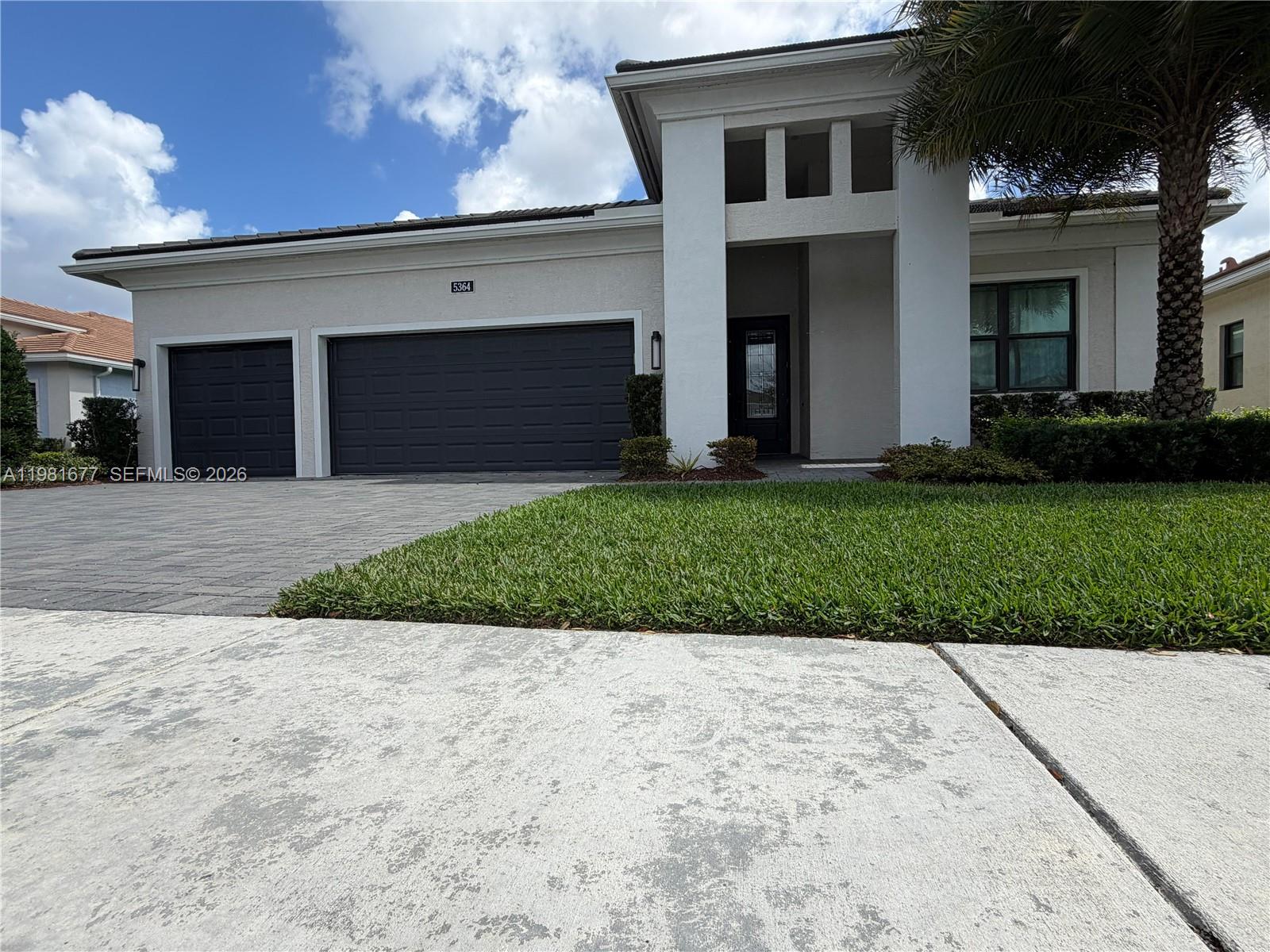 A single-story house features a paved driveway, a three-car garage, and a palm tree — 5364 Siesta Key Ln, Loxahatchee FL 33470, LOXAHATCHEE, FL
