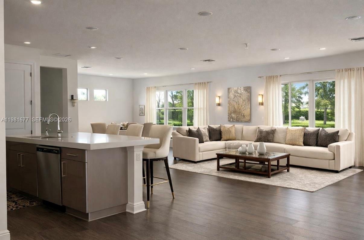An open-concept kitchen and living area featuring a white island, bar stools, and sectional sofa — 5364 Siesta Key Ln, Loxahatchee FL 33470, LOXAHATCHEE, FL
