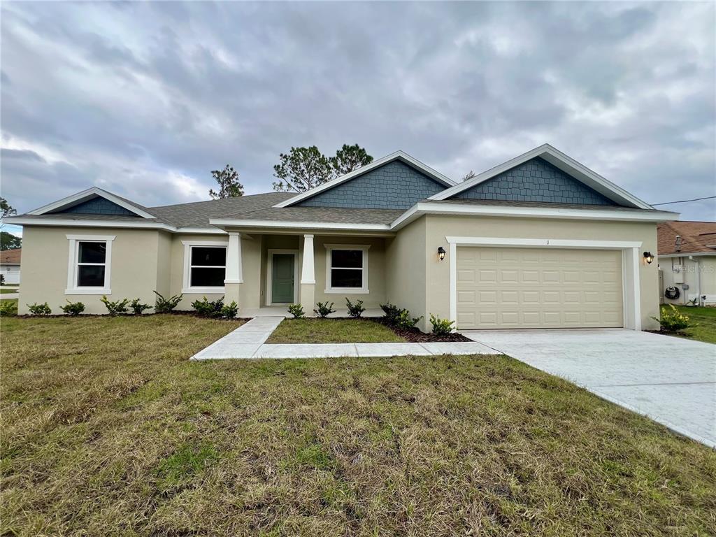 A single-story house with a beige stucco exterior, blue shingle accents, and a two-car garage — 1 SEA FLOWER PATH, PALM COAST, FL