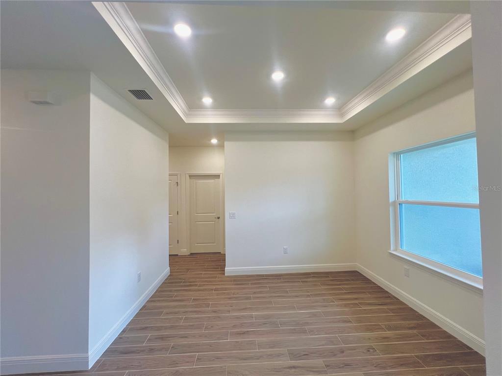 An empty room features a tray ceiling with recessed lighting and wood-look tile flooring — 1 SEA FLOWER PATH, PALM COAST, FL