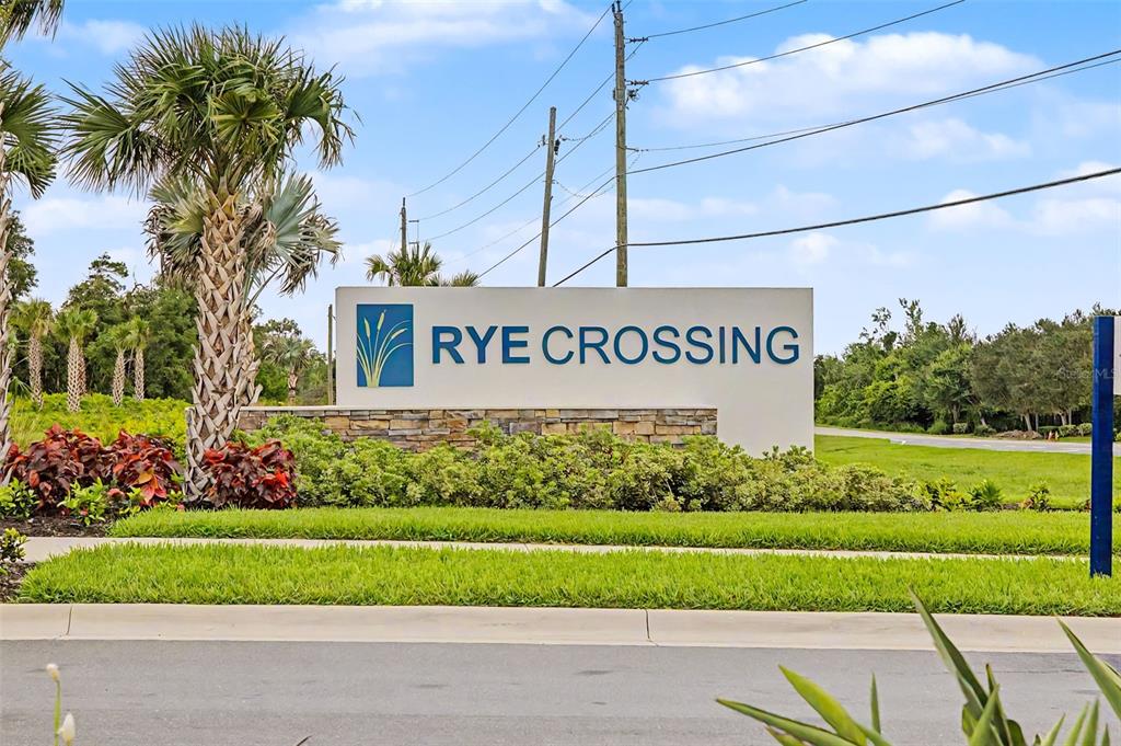 A sign for Rye Crossing stands in a landscaped area with palm trees and grass — 17315 WHEATBERRY BOULEVARD, PARRISH, FL