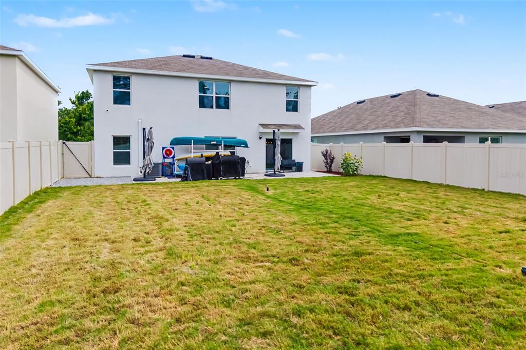 The exterior rear view of a two-story house with a fenced backyard and patio — 17315 WHEATBERRY BOULEVARD, PARRISH, FL