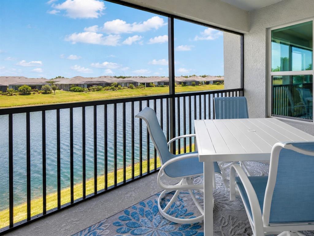 A screened-in balcony features a white table, chairs, and a view of a lake — 14194 HERITAGE LANDING BOULEVARD UNIT 623, PUNTA GORDA, FL