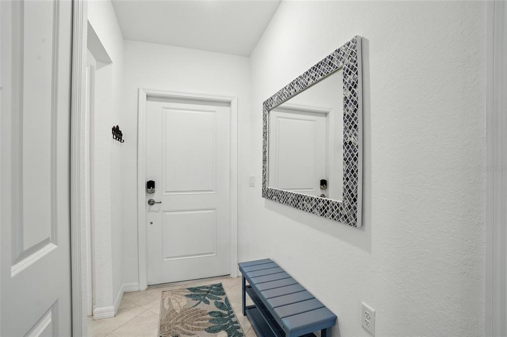 An entryway features a white door, a blue bench, and a decorative mosaic-framed mirror — 14194 HERITAGE LANDING BOULEVARD UNIT 623, PUNTA GORDA, FL