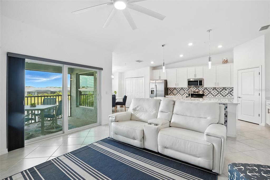 A living room with a white sofa and rug opens to a balcony with outdoor furniture — 14194 HERITAGE LANDING BOULEVARD UNIT 623, PUNTA GORDA, FL