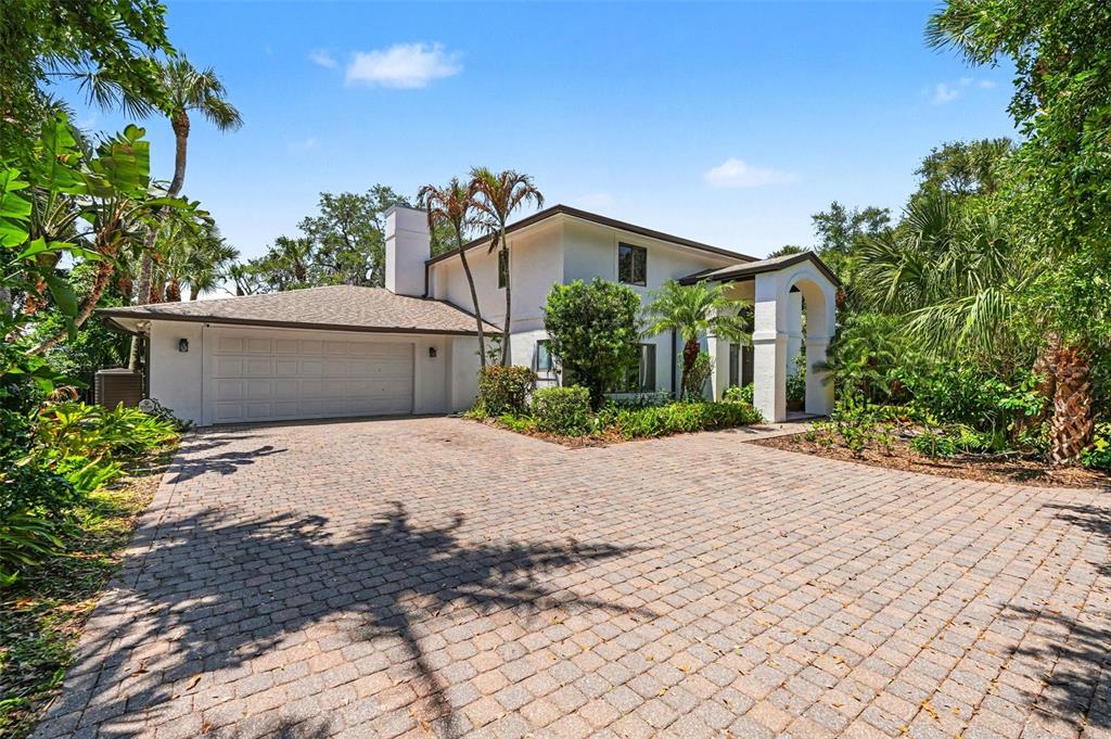 A two-story white house with a paved driveway and lush tropical landscaping — 4137 CROOKED MILE ROAD, MERRITT ISLAND, FL