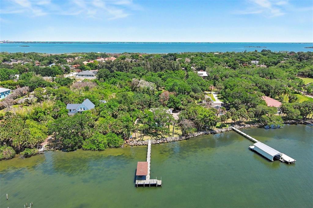 An aerial view shows a waterfront property with two docks extending into the bay — 4137 CROOKED MILE ROAD, MERRITT ISLAND, FL