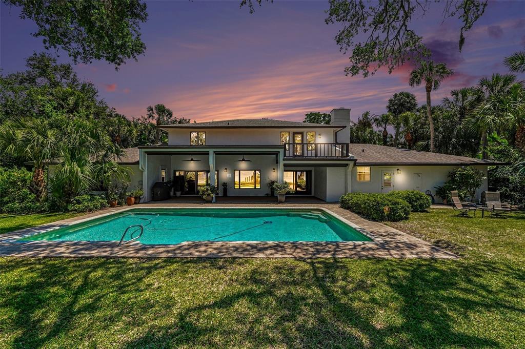 A two-story white house with a swimming pool and a balcony at sunset — 4137 CROOKED MILE ROAD, MERRITT ISLAND, FL