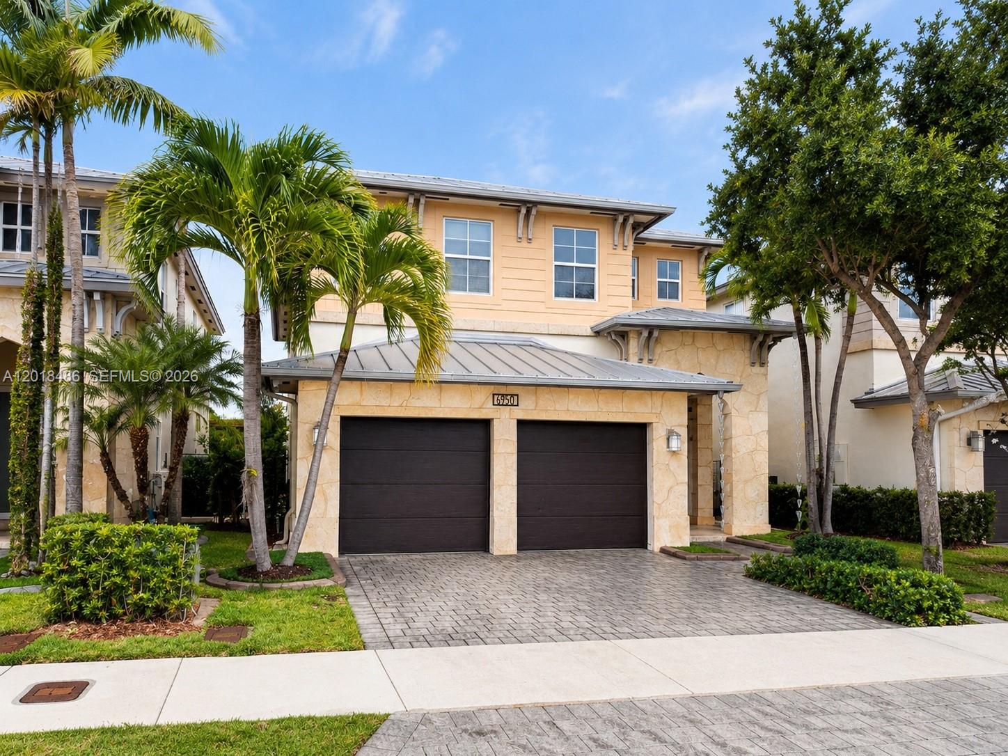 A two-story house with a stone facade, two garage doors, and palm trees in front — 6950 NW 106th Ave, Doral FL 33178, DORAL, FL