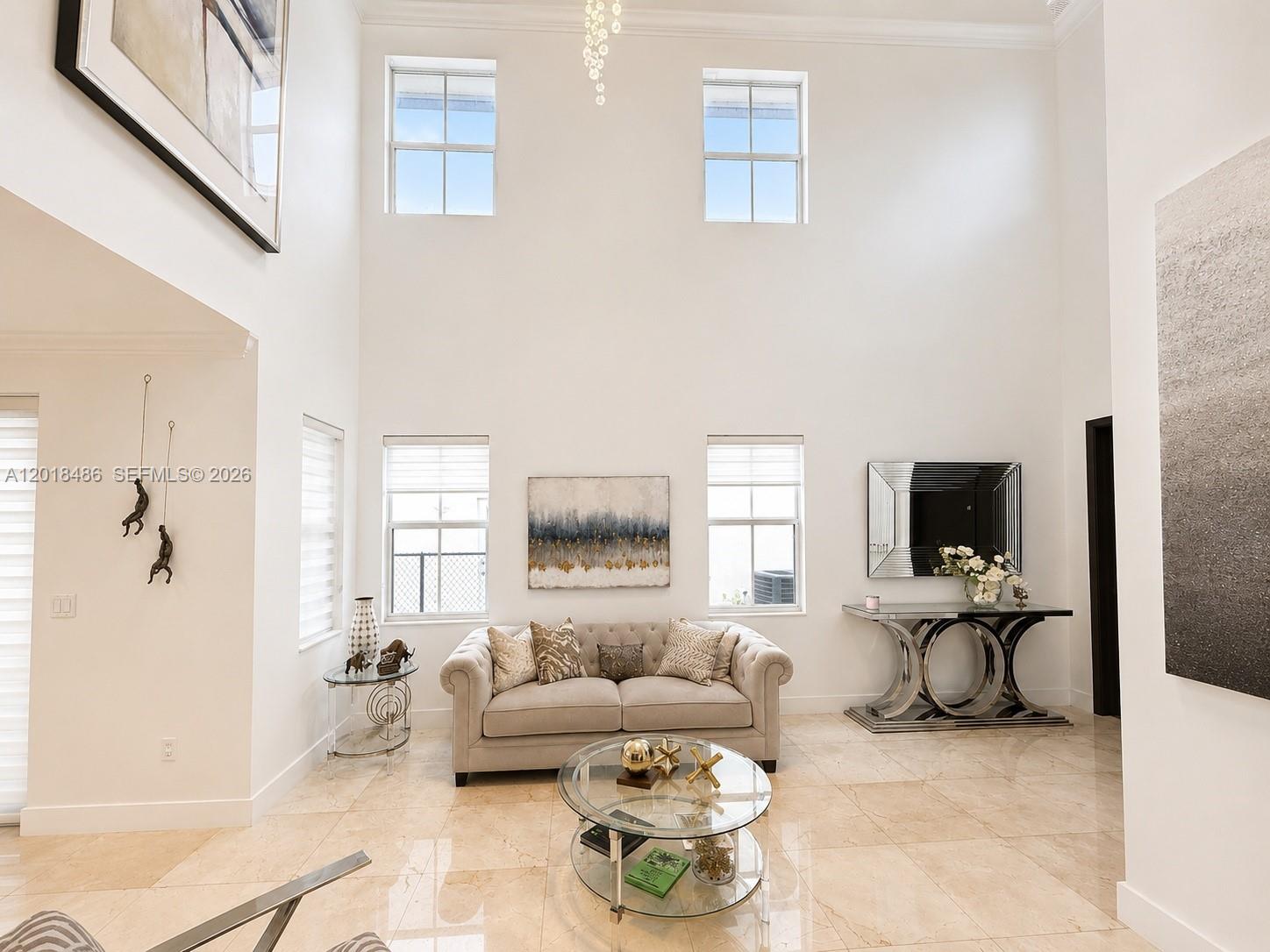 A high-ceilinged living room features a beige sofa, glass coffee table, and tiled floors — 6950 NW 106th Ave, Doral FL 33178, DORAL, FL