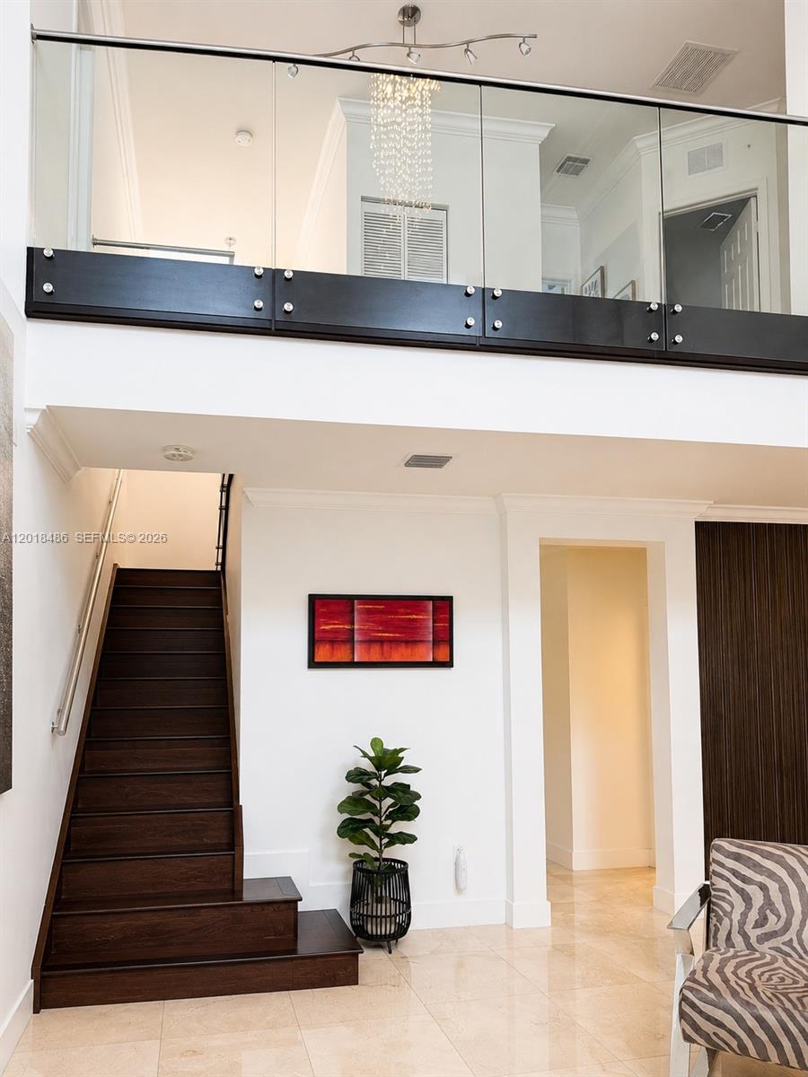 A staircase with dark wood treads leads to a glass-railed landing in a modern foyer — 6950 NW 106th Ave, Doral FL 33178, DORAL, FL