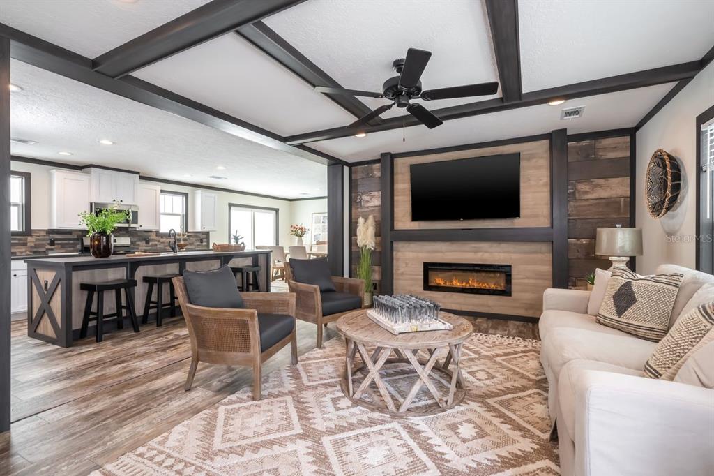 A living room with a fireplace, wood-paneled wall, and an open kitchen with an island — 18088 NW 304TH STREET, OKEECHOBEE, FL