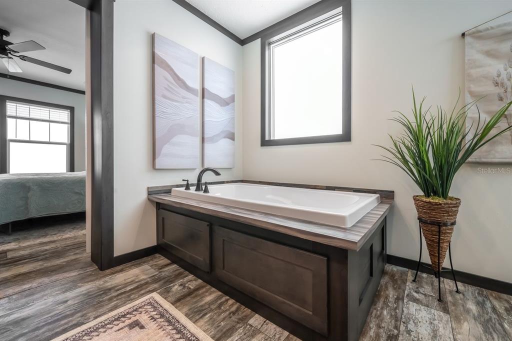 A bathroom features a built-in soaking tub with dark wood cabinetry and a window above — 18088 NW 304TH STREET, OKEECHOBEE, FL