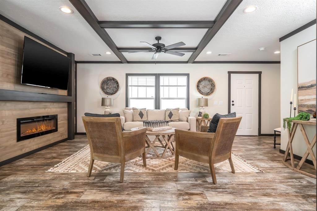 A living room features a fireplace, wood-look flooring, a coffered ceiling, and two cane chairs — 18088 NW 304TH STREET, OKEECHOBEE, FL
