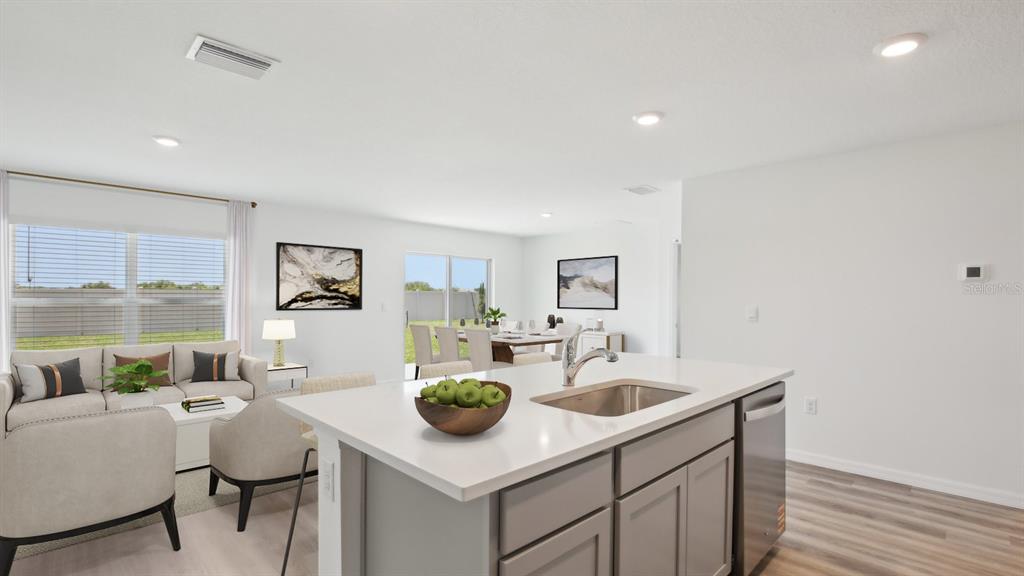 A kitchen island with a sink overlooks a living room and dining area — 1011 GUM SPRING COURT, RUSKIN, FL