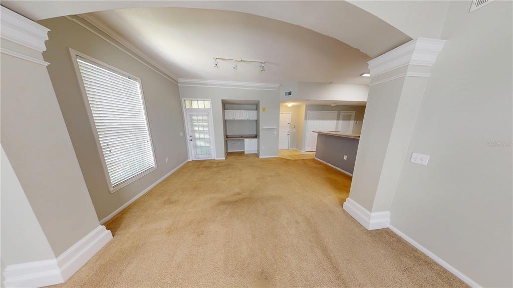 A carpeted living area features a built-in desk, a glass-paned door, and an arched entryway — 235 GOLDENRAIN DRIVE UNIT 303, CELEBRATION, FL