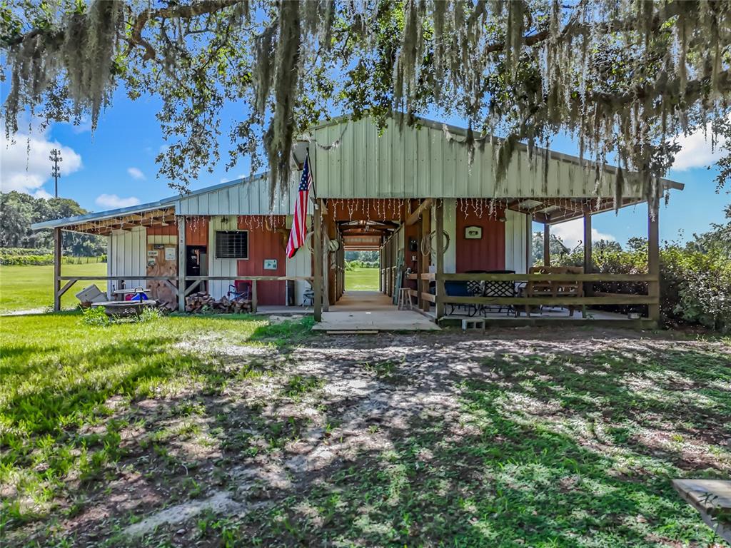 A rustic barn with a covered porch and an American flag under hanging Spanish moss — 41204 EMERALDA ISLAND ROAD, LEESBURG, FL