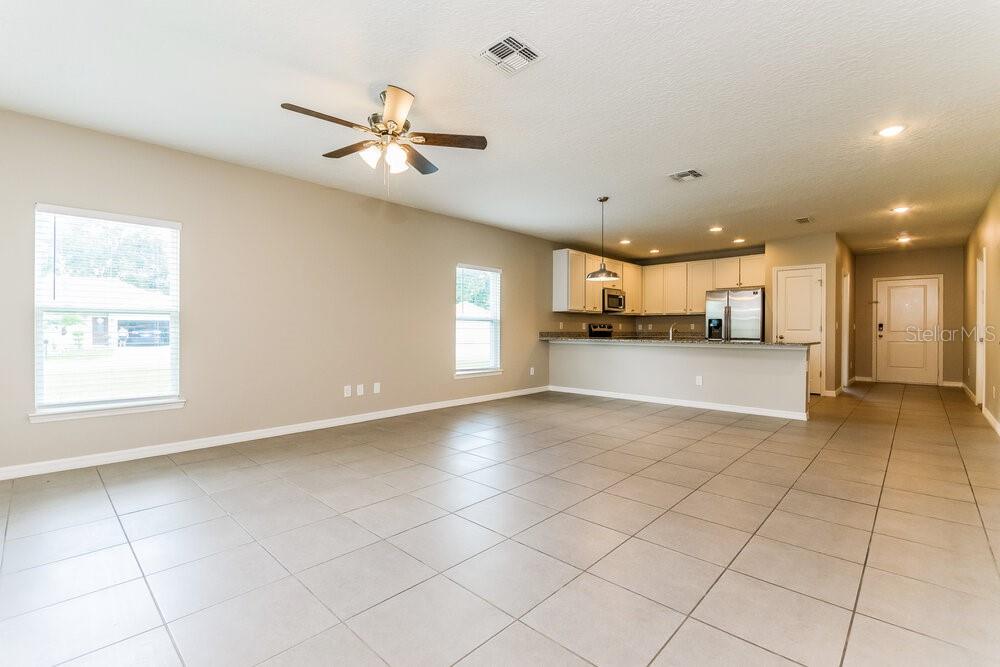 An open-concept living area features light-colored tile flooring, a ceiling fan, and a kitchen — 126 BRIARCLIFF DRIVE, KISSIMMEE, FL