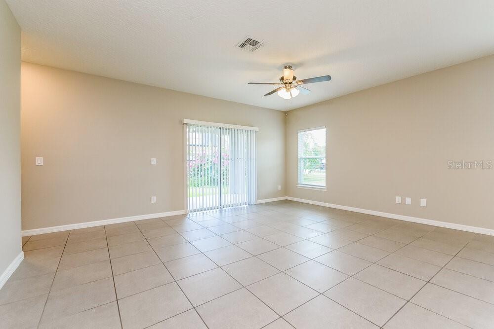An empty living room features beige walls, large light-colored floor tiles, and a ceiling fan — 126 BRIARCLIFF DRIVE, KISSIMMEE, FL