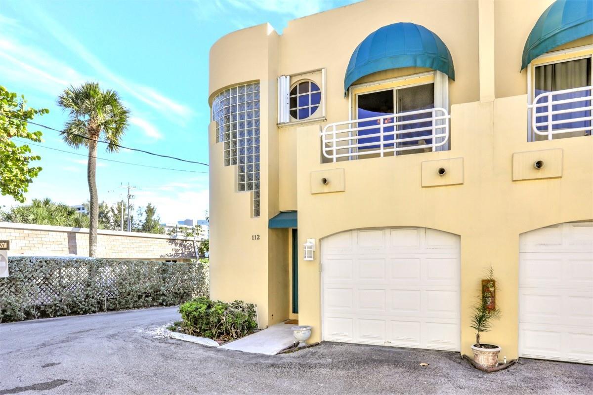 A two-story yellow stucco townhouse features a garage, a balcony, and glass block windows — 3213 NE 16th Street # 112, Pompano Beach FL 33062, POMPANO BEACH, FL