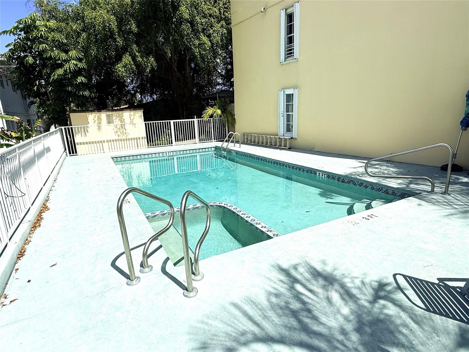 An outdoor swimming pool with a shallow entry area is surrounded by a concrete deck — 3213 NE 16th Street # 112, Pompano Beach FL 33062, POMPANO BEACH, FL