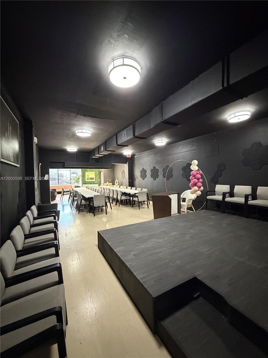 A black-walled event space features a raised stage, rows of chairs, and long dining tables — 519 S 21st Ave, Hollywood FL 33020, HOLLYWOOD, FL