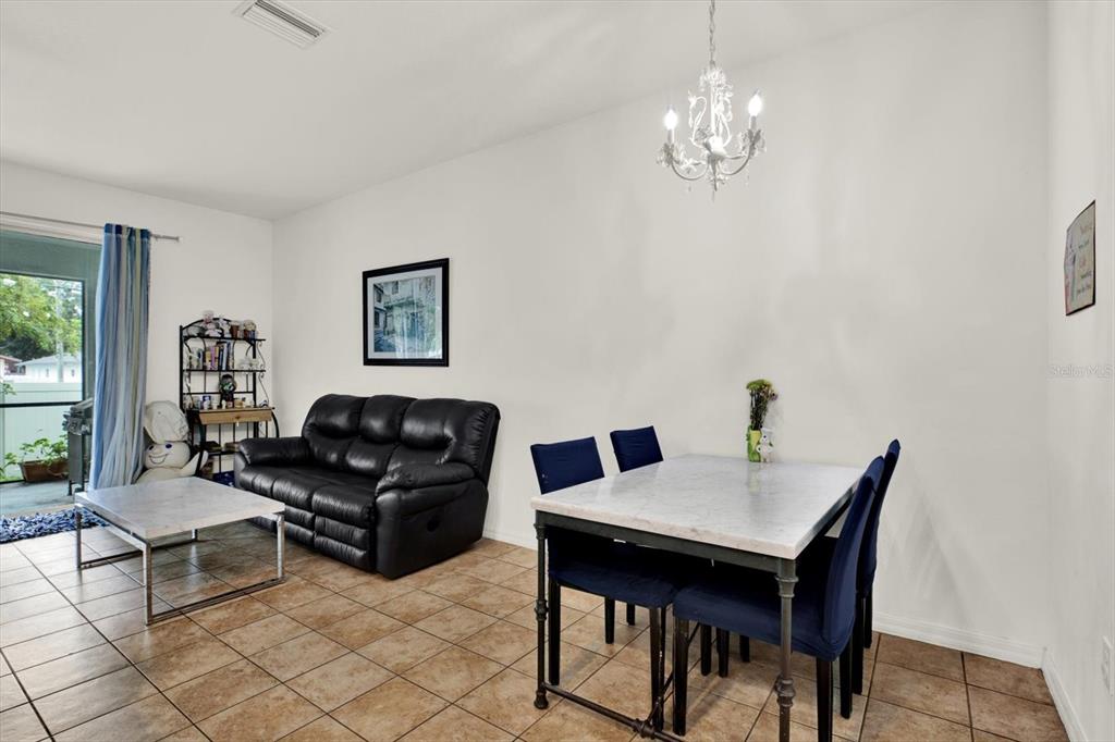 A living and dining area features tile flooring, a black sofa, and a marble-topped table — 6843 46TH LANE N, PINELLAS PARK, FL