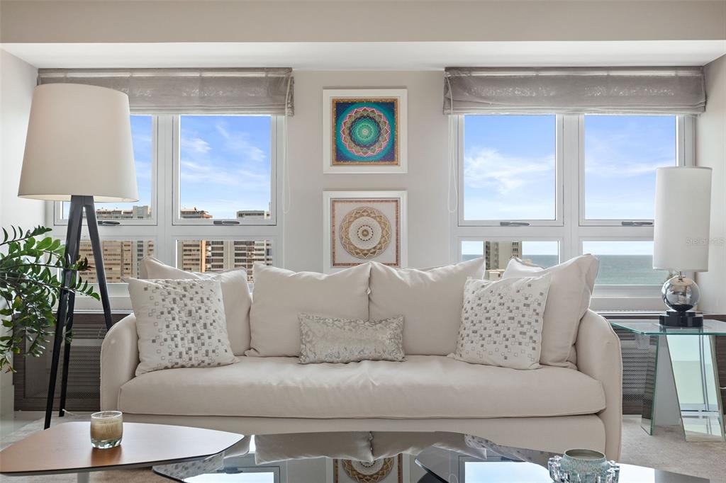 A living room features a white sofa, two windows with ocean views, and two framed artworks — Gallery Plaza DE DIEGO AVE. UNIT 1203-N, SAN JUAN, PR