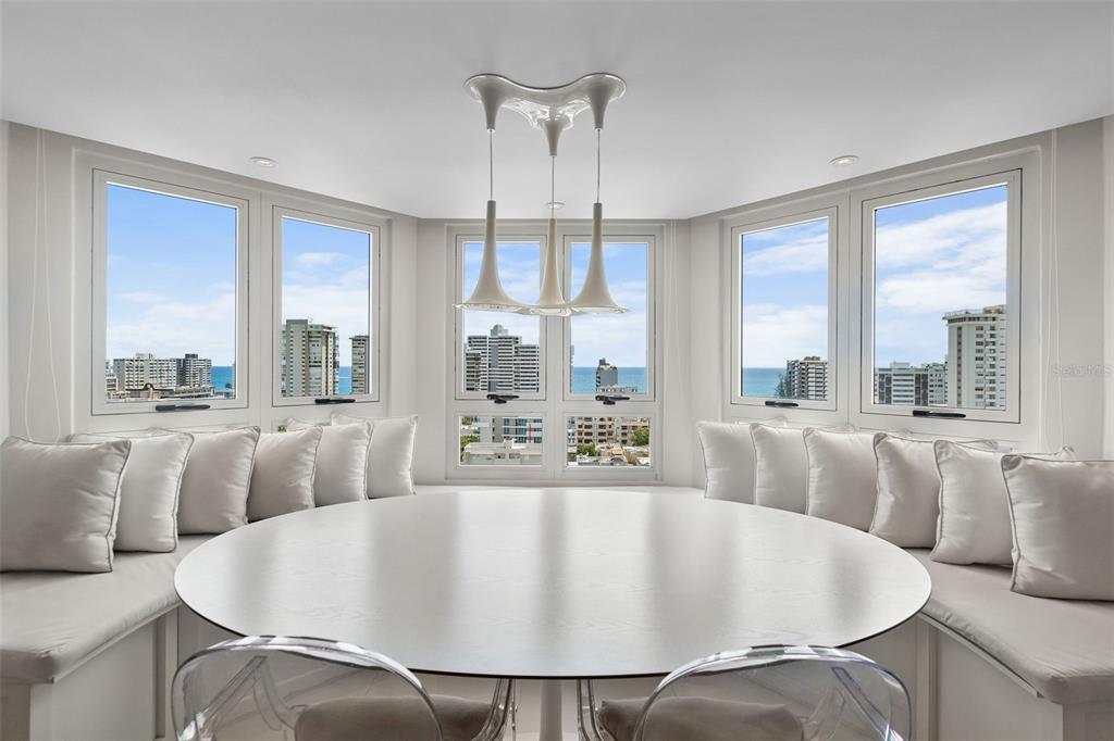 A dining area features a round table, built-in bench seating, and windows overlooking the ocean — Gallery Plaza DE DIEGO AVE. UNIT 1203-N, SAN JUAN, PR