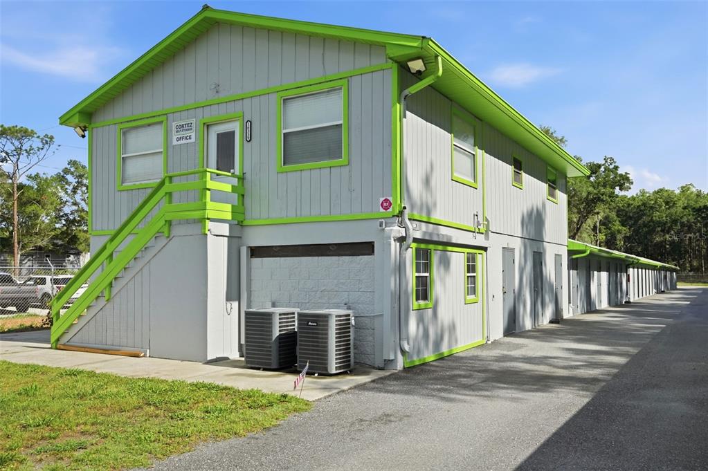 A two-story building with gray siding, lime green trim, an exterior staircase, and storage units — 16331 CORTEZ BOULEVARD, BROOKSVILLE, FL