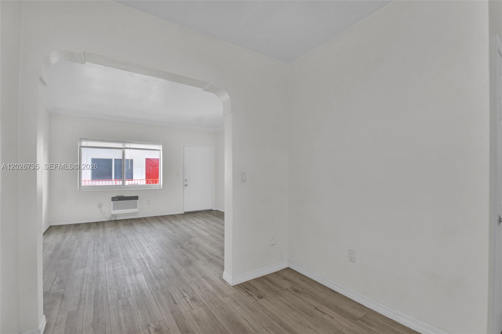 An interior view shows a room with light wood-look flooring and an arched doorway — 1135 Euclid Ave # 202, Miami Beach FL 33139, MIAMI BEACH, FL