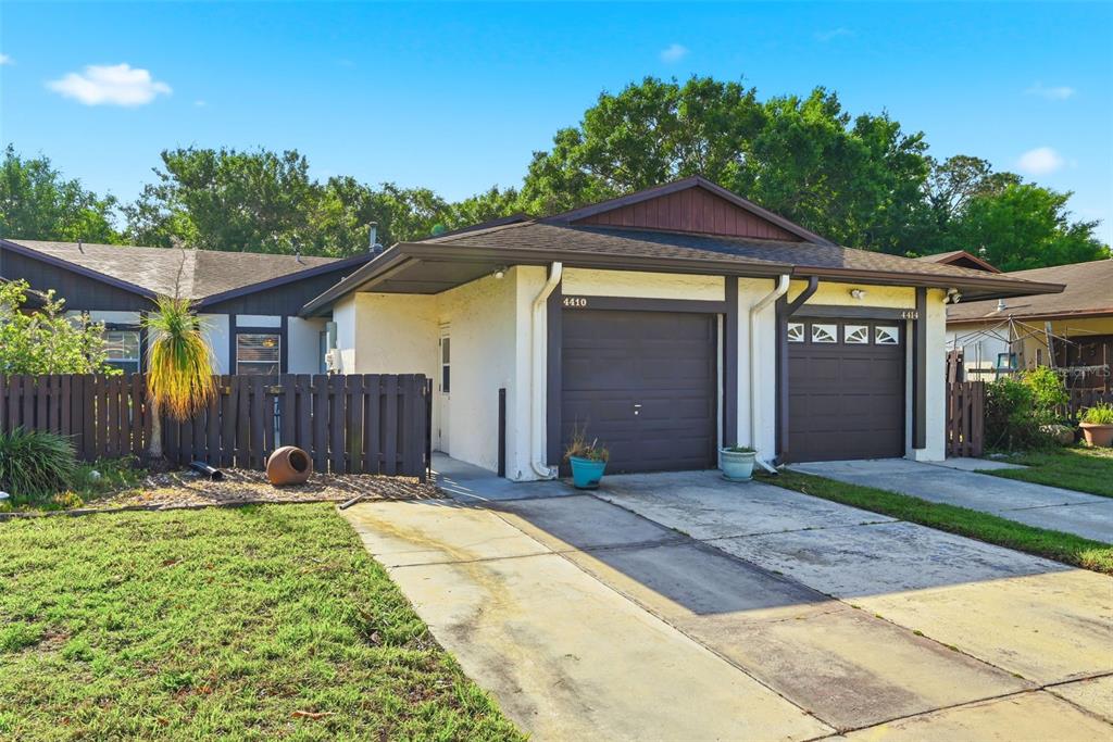 A duplex with two brown garage doors, a wooden fence, and a concrete driveway — 4410 BAR HARBOR DRIVE, ORLANDO, FL