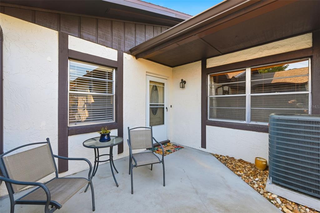 A patio with two chairs, a small table, and an air conditioning unit outside — 4410 BAR HARBOR DRIVE, ORLANDO, FL