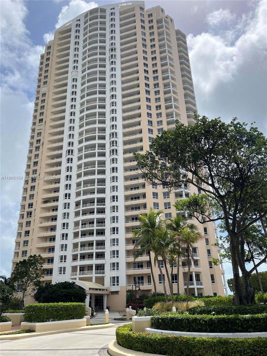 A tall, beige residential high-rise building stands behind a landscaped driveway and palm trees — 808 Brickell Key Dr # 2002, Miami FL 33131, MIAMI, FL