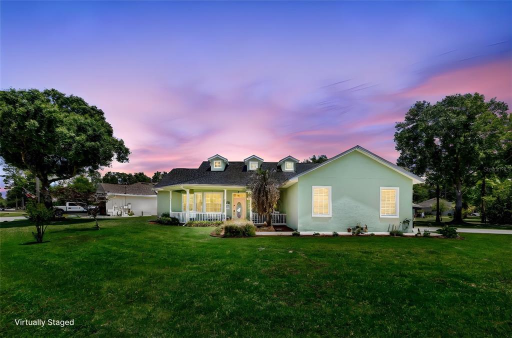 A light green house with a dark roof sits on a grassy lawn at sunset — 54 EDITH POPE DRIVE, PALM COAST, FL