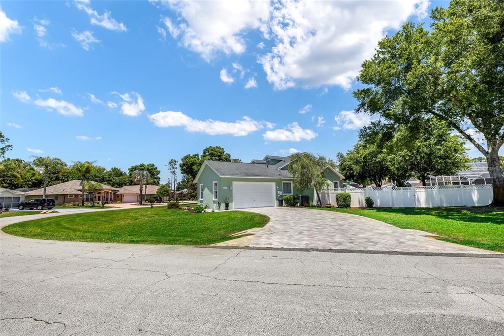 A light green house with a paved driveway and a white fence under a blue sky — 54 EDITH POPE DRIVE, PALM COAST, FL