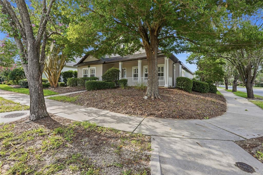 A single-story house with a front porch sits on a corner lot with trees — 8693 SW 76TH PLACE, GAINESVILLE, FL