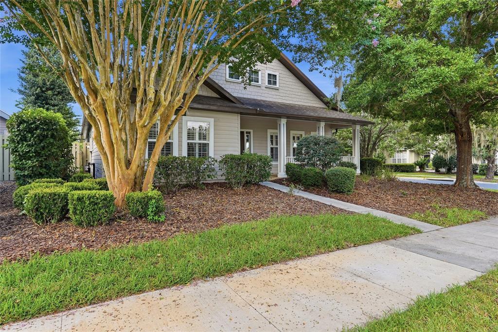 A light-colored house with a front porch, a large tree, and a sidewalk in front — 8693 SW 76TH PLACE, GAINESVILLE, FL