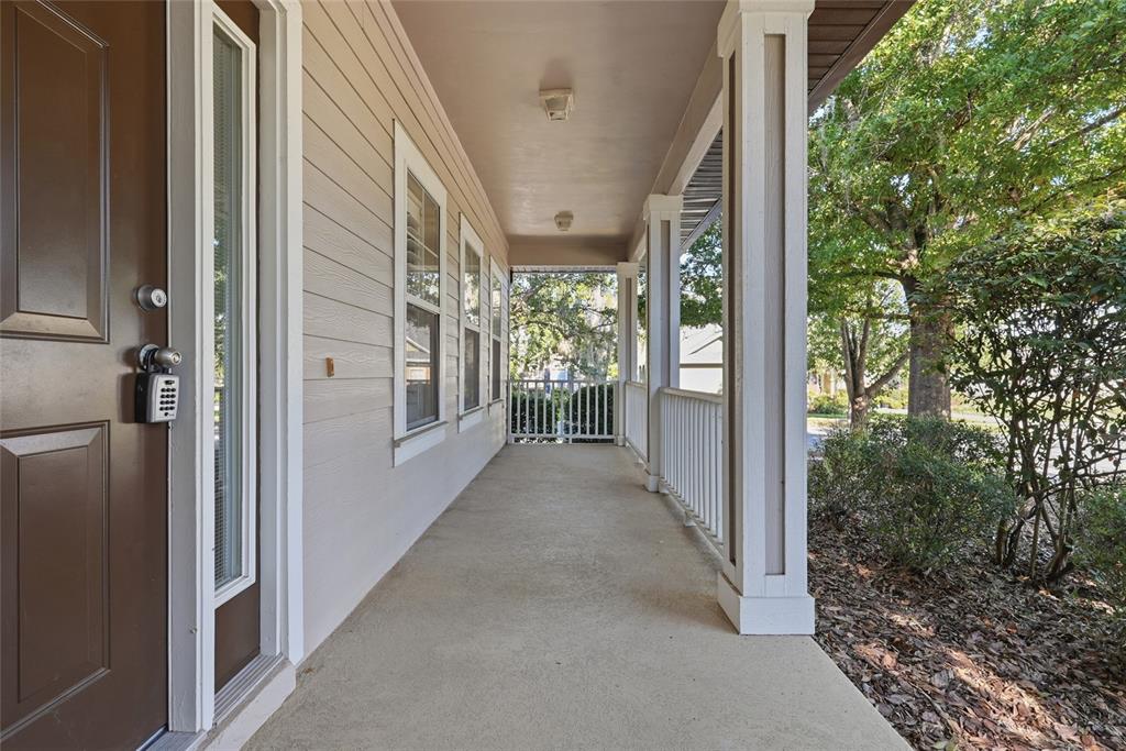 A covered front porch features a brown door, light-colored siding, and white railings — 8693 SW 76TH PLACE, GAINESVILLE, FL